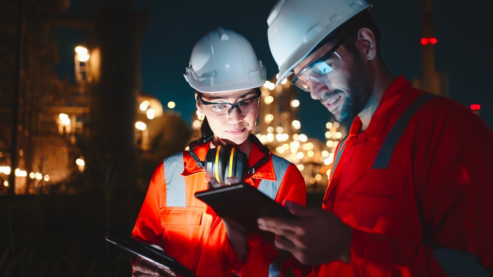 Two engineers reviewing information on a tablet at an industrial facility